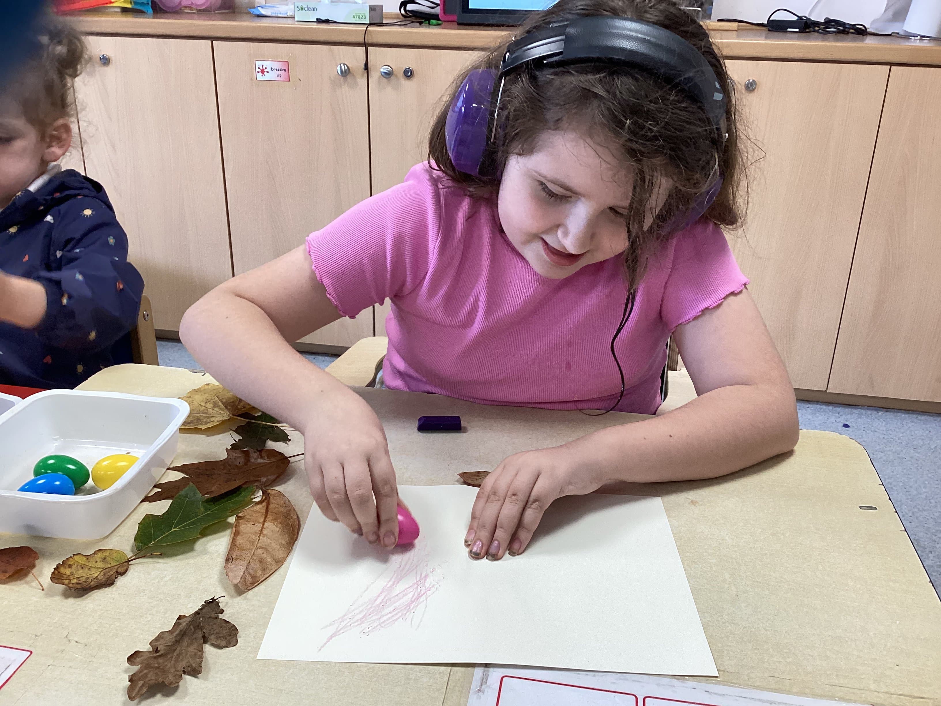 Girl doing leaf rubbing art with headphones
