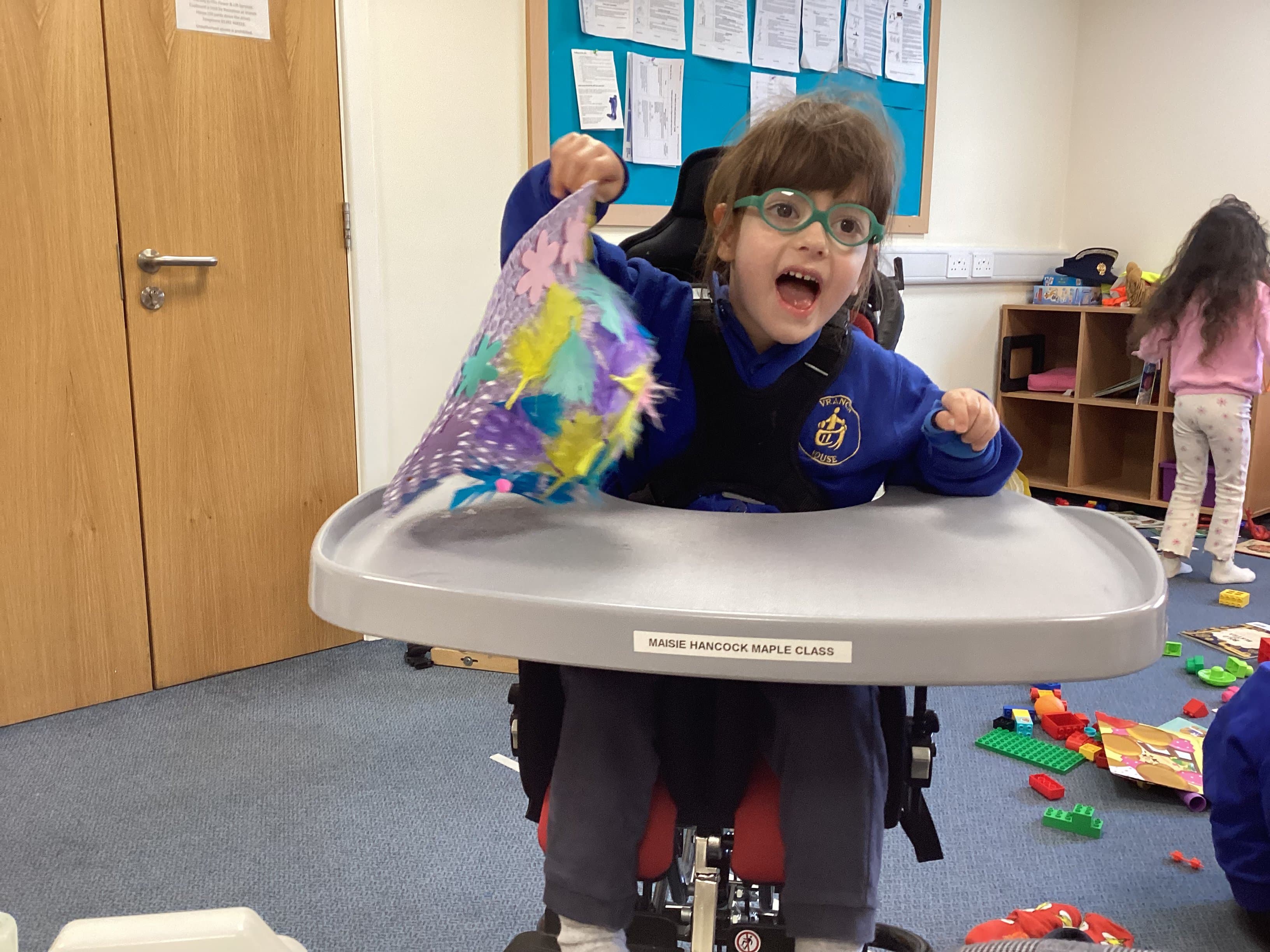 Girl proudly showing her feathered craft in Maple Class